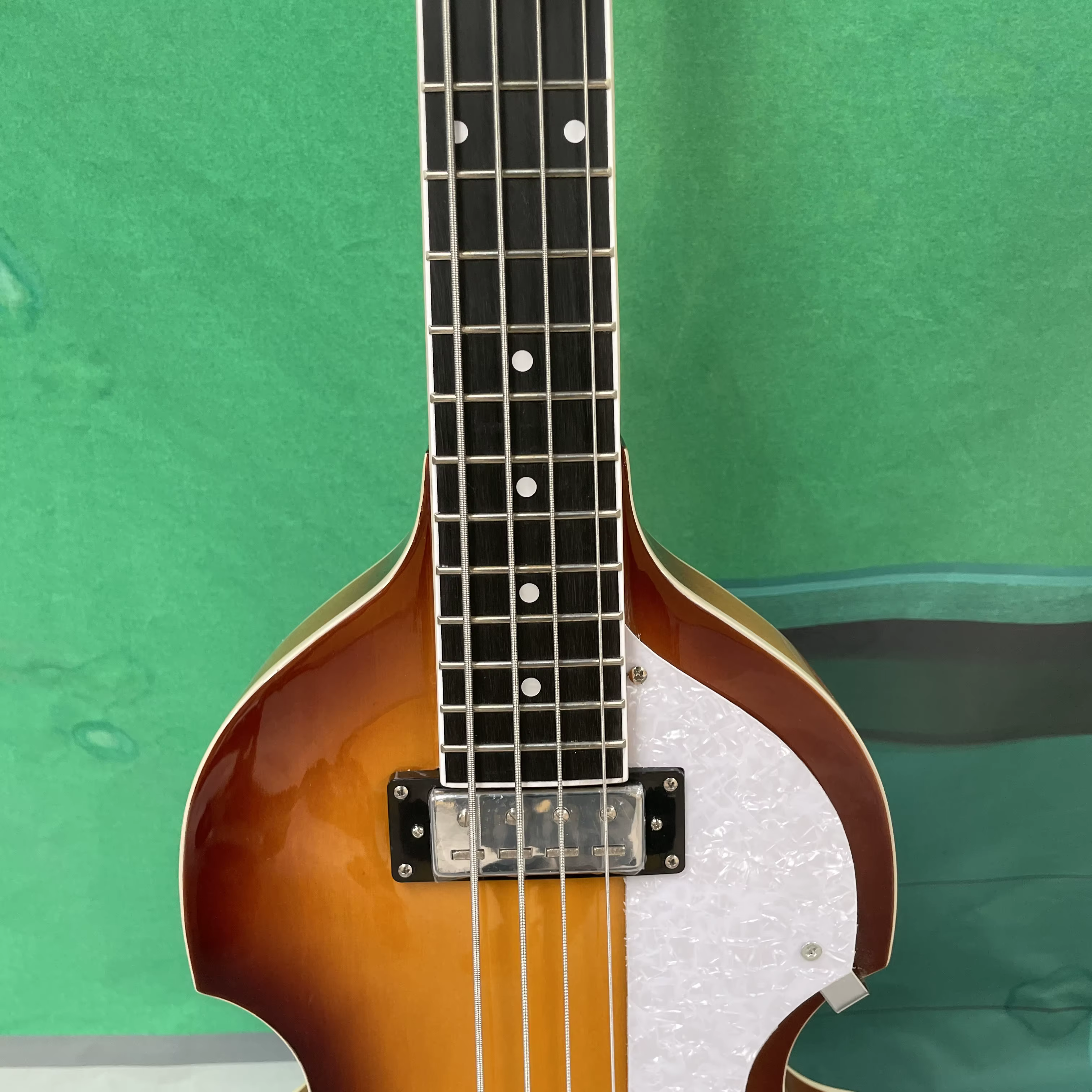 Guitare basse électrique à 4 cordes, corps de style violon, pickguard blanc, quincaillerie argentée, idéale pour les guitaristes débutants.